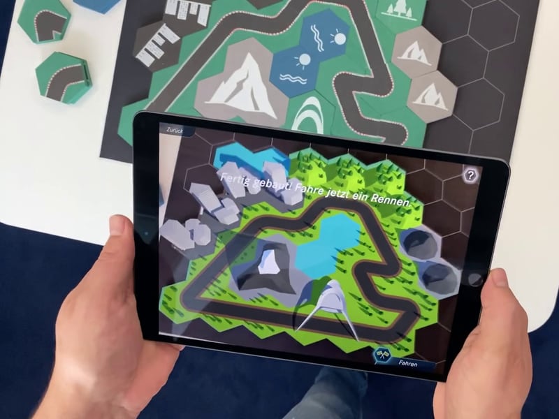 An iPad running the AR module which recognized the physical racetrack made of hexagonal tiles.